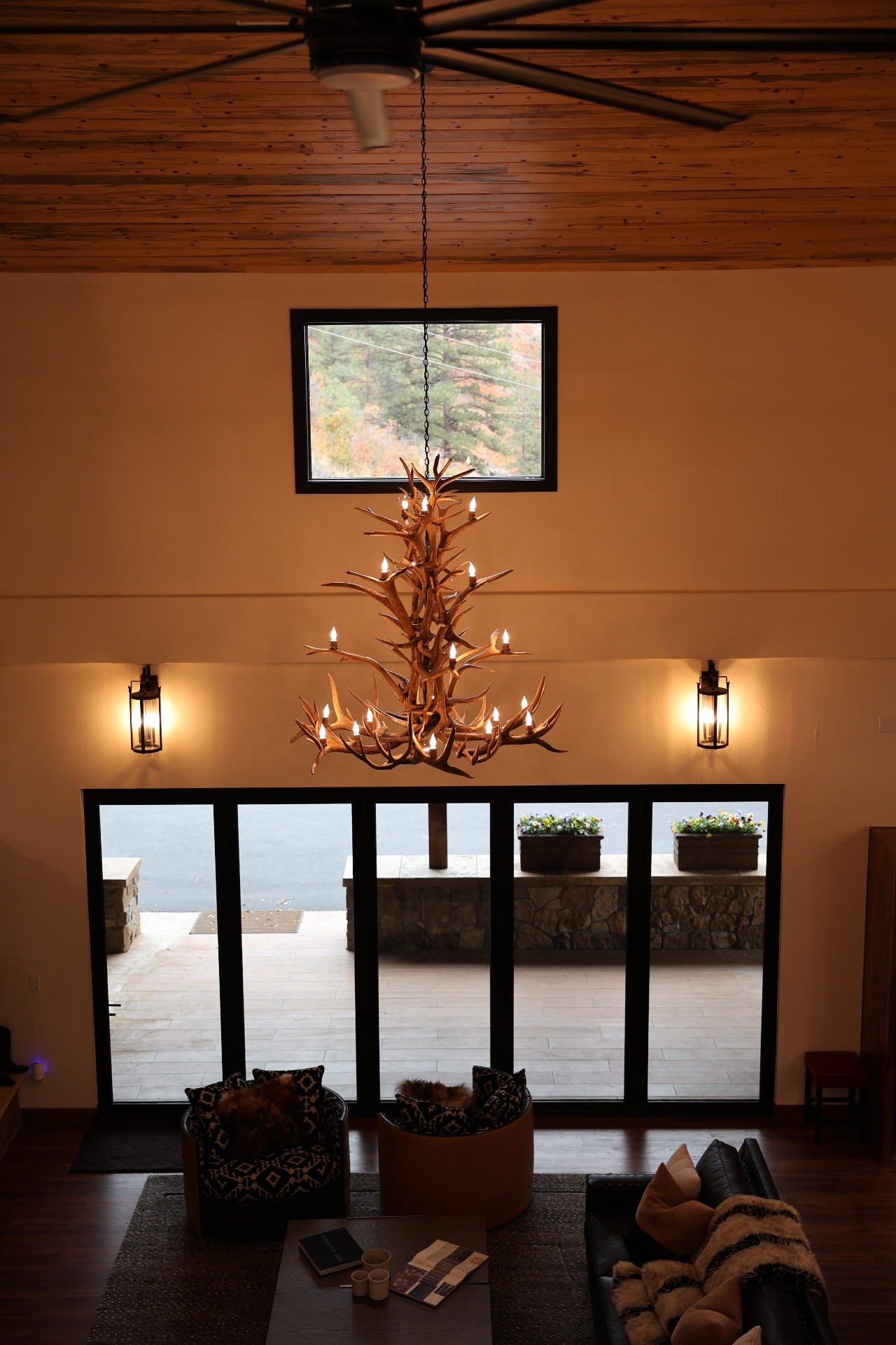 Warm residential interior lit by an antler chandelier and black sconces installed by iPowerDenver